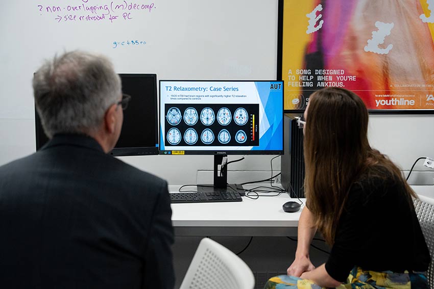 Two people looking at a computer with a brain scan on the screen. 